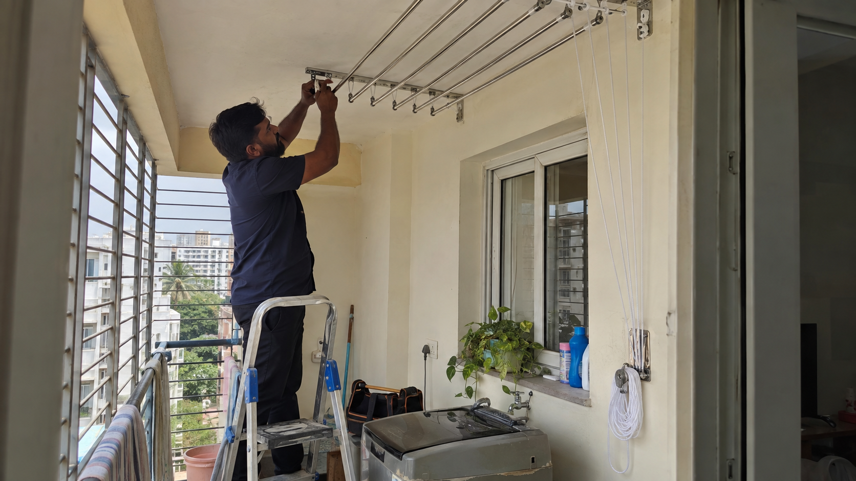 Technician installing a ceiling cloth drying hanger in a Bangalore apartment